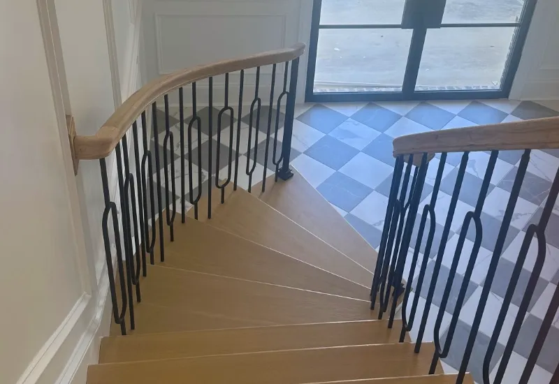 A custom winding staircase with a modern touch of iron posts.